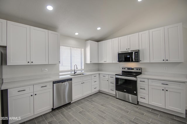 kitchen featuring stainless steel appliances, light countertops, a sink, and white cabinetry
