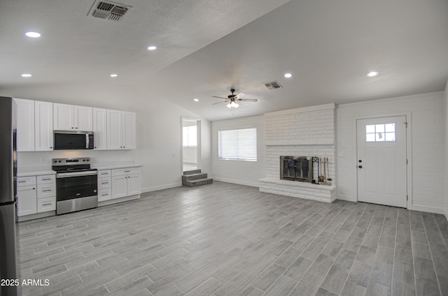 kitchen featuring stainless steel appliances, visible vents, baseboards, open floor plan, and ceiling fan