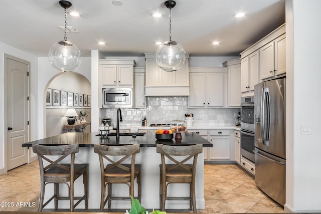 kitchen with decorative backsplash, a kitchen breakfast bar, appliances with stainless steel finishes, and a sink