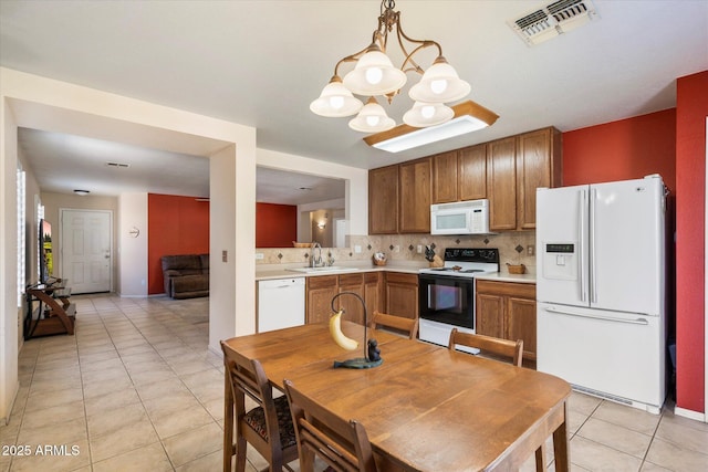 kitchen featuring a sink, visible vents, white appliances, and light countertops