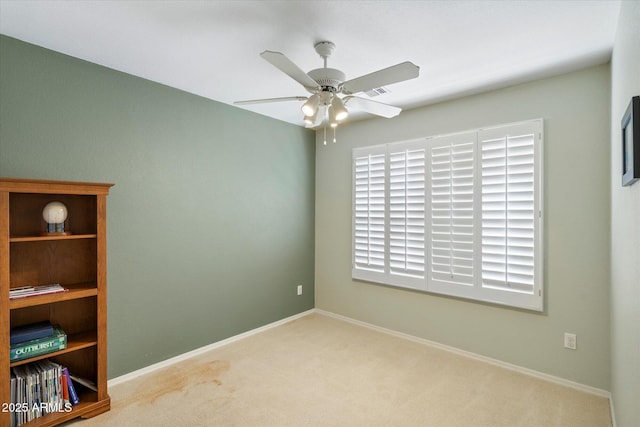 carpeted spare room featuring ceiling fan and baseboards