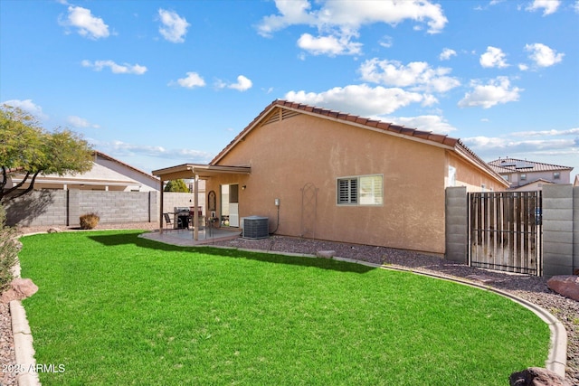 rear view of house with stucco siding, a gate, fence, a yard, and a patio area