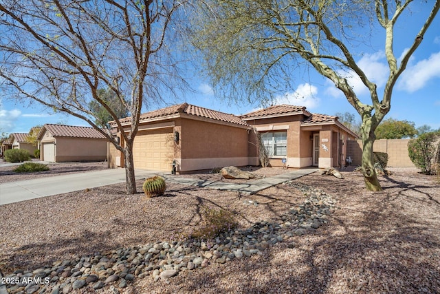 view of front of house featuring fence, a tiled roof, concrete driveway, stucco siding, and a garage