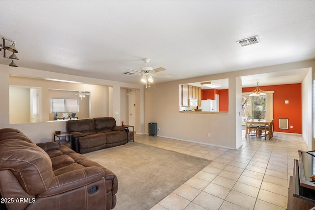 living room with light tile patterned floors, visible vents, baseboards, and a ceiling fan