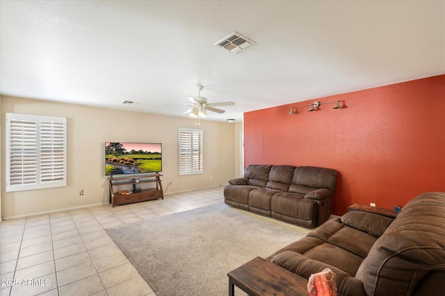 living area featuring tile patterned flooring, a ceiling fan, visible vents, and baseboards