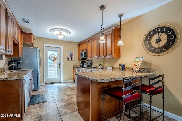 kitchen featuring sink, stainless steel appliances, a kitchen breakfast bar, kitchen peninsula, and pendant lighting