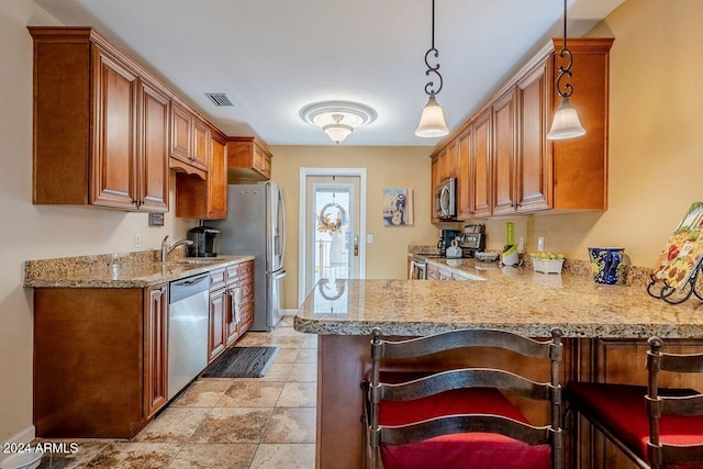 kitchen with sink, hanging light fixtures, light stone countertops, kitchen peninsula, and stainless steel appliances