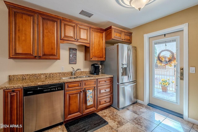 kitchen featuring sink, light stone countertops, and stainless steel appliances