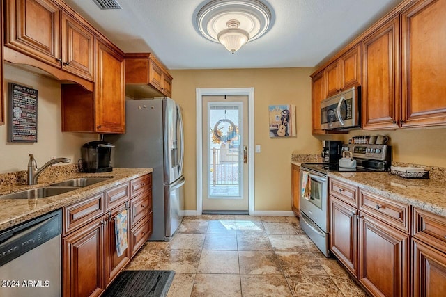 kitchen featuring light stone countertops, stainless steel appliances, and sink