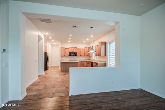 kitchen with pendant lighting, light hardwood / wood-style flooring, black appliances, kitchen peninsula, and light brown cabinets