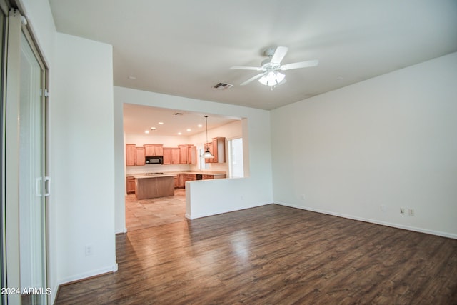 unfurnished living room featuring ceiling fan and wood-type flooring