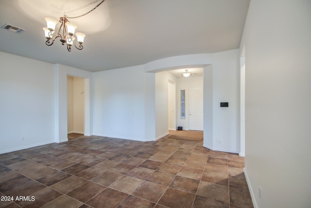 unfurnished room with a notable chandelier