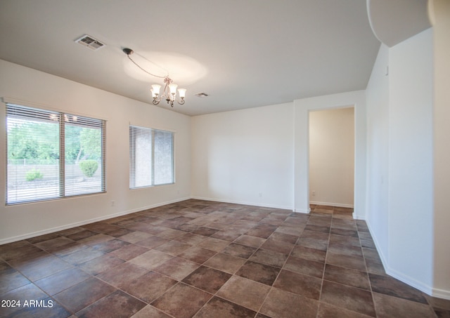 unfurnished room with an inviting chandelier