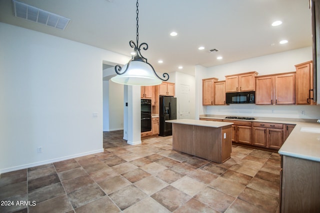 kitchen featuring sink, decorative light fixtures, black appliances, and a center island