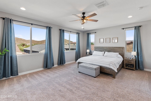 bedroom featuring ceiling fan, light carpet, and a mountain view