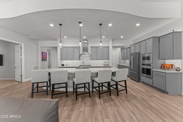 3326 Josey Wales Way, Wickenburg, AZ 85390 - kitchen featuring stainless steel appliances, wall chimney range hood, gray cabinetry, backsplash, and light wood-style flooring