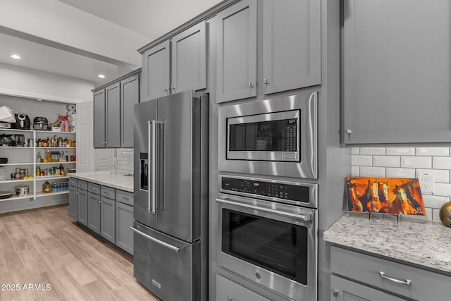 3326 Josey Wales Way, Wickenburg, AZ 85390 - kitchen with appliances with stainless steel finishes, gray cabinets, decorative backsplash, light stone countertops, and light wood-type flooring