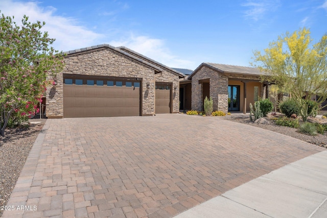 3326 Josey Wales Way, Wickenburg, AZ 85390 - view of front facade featuring a garage, decorative driveway, solar panels, and stone siding