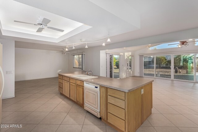 kitchen featuring a kitchen island, light tile patterned floors, a raised ceiling, dishwasher, and sink