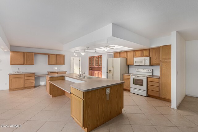 kitchen featuring an island with sink, ceiling fan, light tile patterned flooring, sink, and white appliances