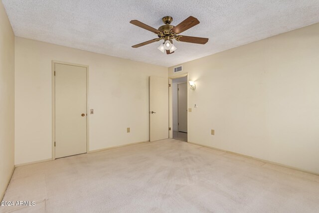 carpeted empty room featuring ceiling fan and a textured ceiling