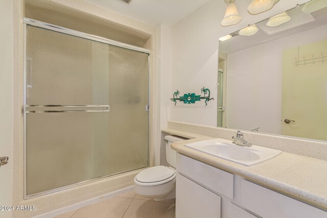 bathroom with vanity, tile patterned flooring, toilet, and an enclosed shower