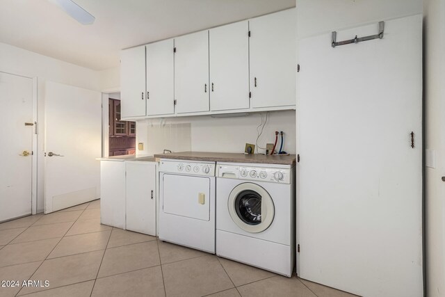 laundry room featuring washing machine and clothes dryer, light tile patterned floors, and cabinets