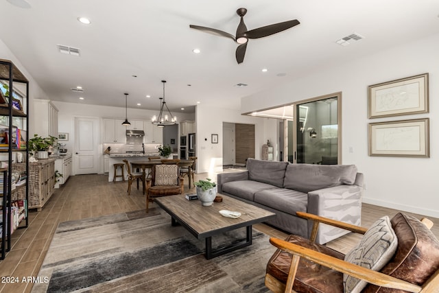 living room featuring hardwood / wood-style floors and ceiling fan with notable chandelier