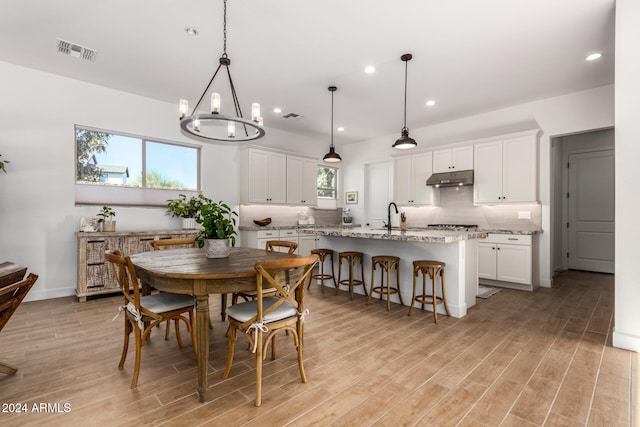 dining area with a notable chandelier, sink, and light hardwood / wood-style flooring