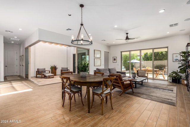 dining area with ceiling fan with notable chandelier and light hardwood / wood-style flooring