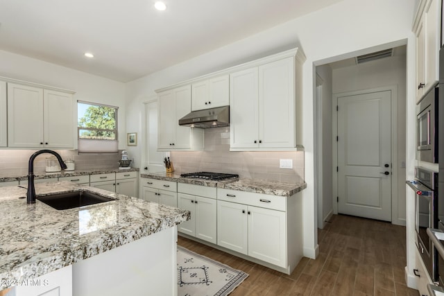 kitchen featuring dark hardwood / wood-style flooring, backsplash, light stone counters, sink, and white cabinets