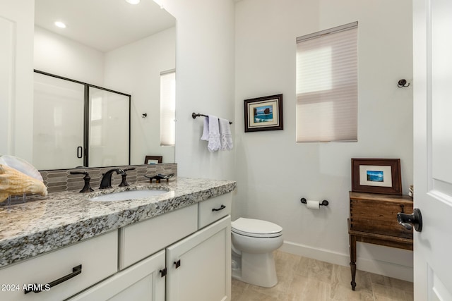 bathroom with a shower with door, vanity, and toilet