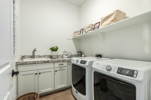 laundry area with washer and dryer, light hardwood / wood-style floors, cabinets, and sink