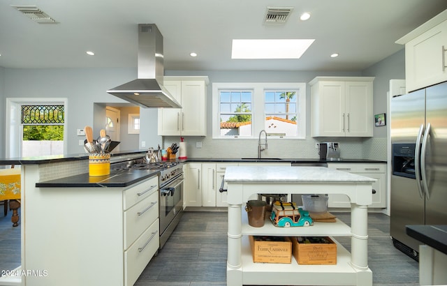 kitchen with appliances with stainless steel finishes, kitchen peninsula, a healthy amount of sunlight, and island range hood