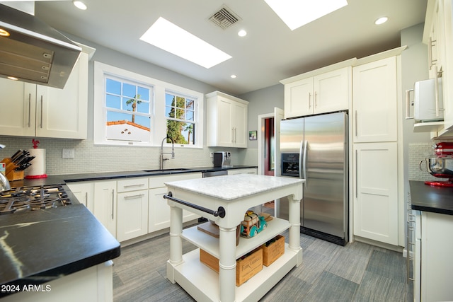 kitchen with a kitchen island, ventilation hood, stainless steel fridge with ice dispenser, and white cabinets