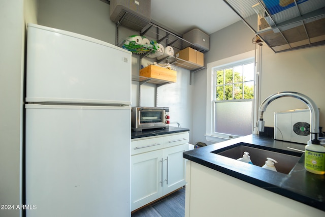 kitchen featuring a wall unit AC, white cabinets, sink, and white refrigerator