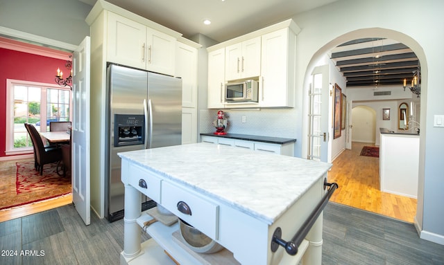 kitchen featuring decorative backsplash, dark hardwood / wood-style floors, beam ceiling, stainless steel appliances, and white cabinets