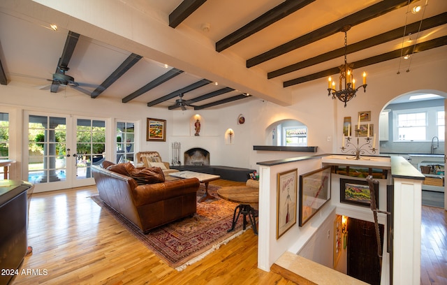 living room featuring beam ceiling, a healthy amount of sunlight, and light wood-type flooring