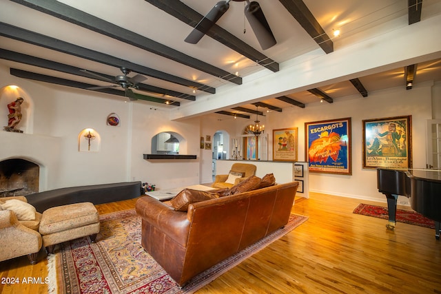 living room featuring beam ceiling, light hardwood / wood-style flooring, and ceiling fan with notable chandelier