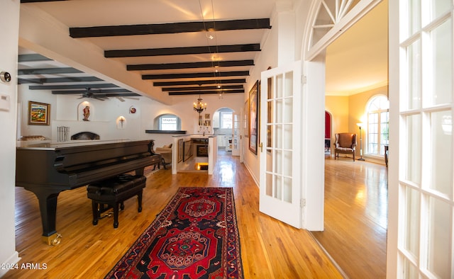 interior space with beamed ceiling, french doors, wood-type flooring, and ceiling fan with notable chandelier