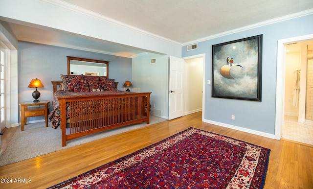 bedroom featuring ornamental molding, connected bathroom, and light wood-type flooring