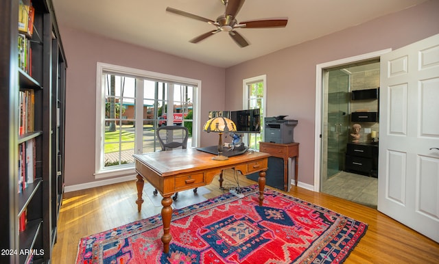 home office with light hardwood / wood-style floors and ceiling fan