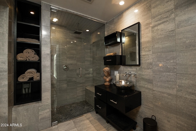 bathroom featuring vanity, tile patterned floors, tile walls, and a shower with shower door