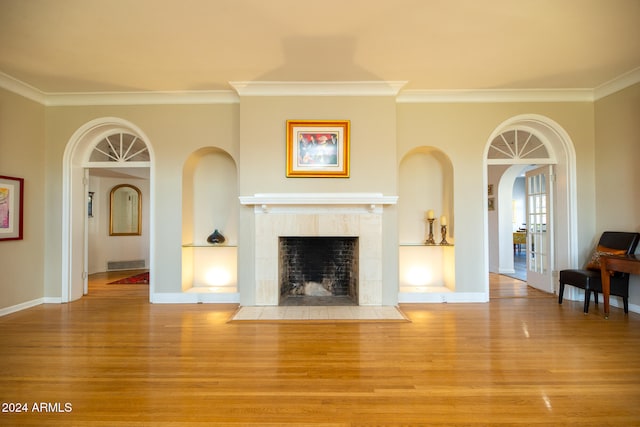 unfurnished living room with a tiled fireplace, crown molding, and light hardwood / wood-style flooring