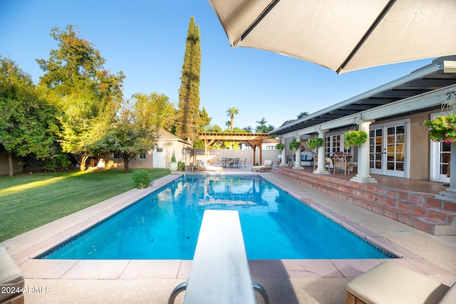 view of pool featuring a patio, a diving board, an outbuilding, and a yard