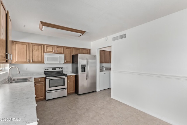 kitchen with separate washer and dryer, appliances with stainless steel finishes, light countertops, a sink, and visible vents