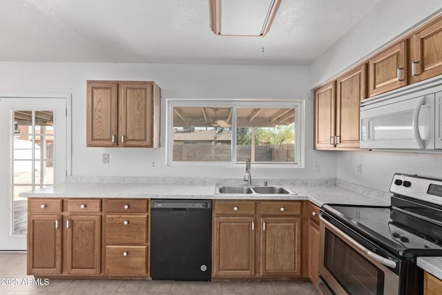 kitchen featuring a sink, stainless steel range with electric stovetop, black dishwasher, white microwave, and brown cabinetry