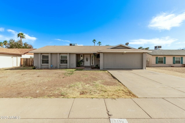 single story home featuring concrete driveway, a garage, and fence