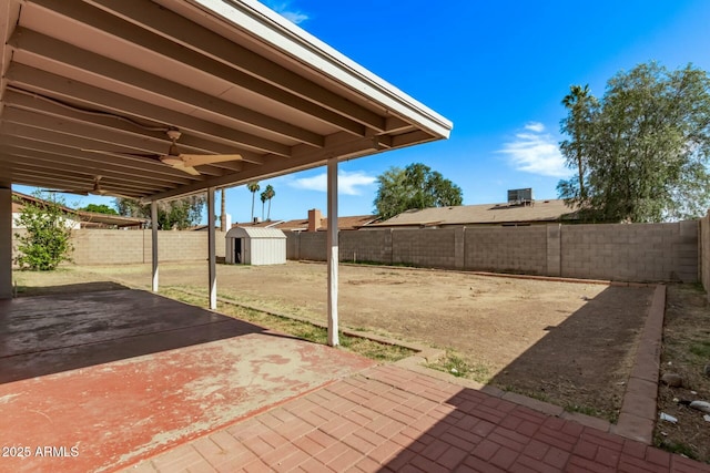 view of patio / terrace with an outbuilding, a shed, ceiling fan, and a fenced backyard