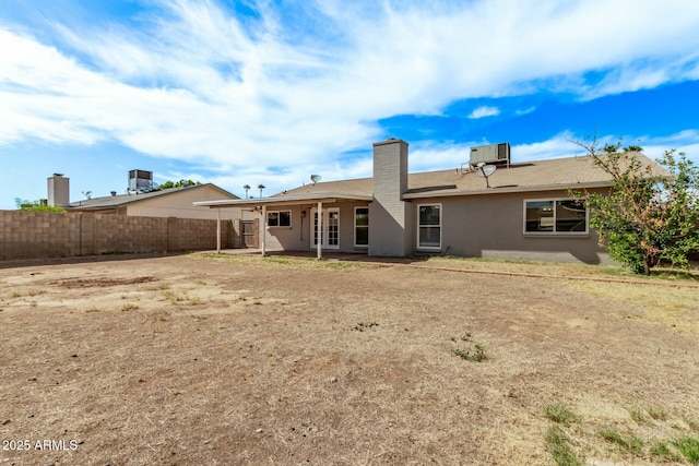 back of property with fence, a chimney, central AC unit, and a patio
